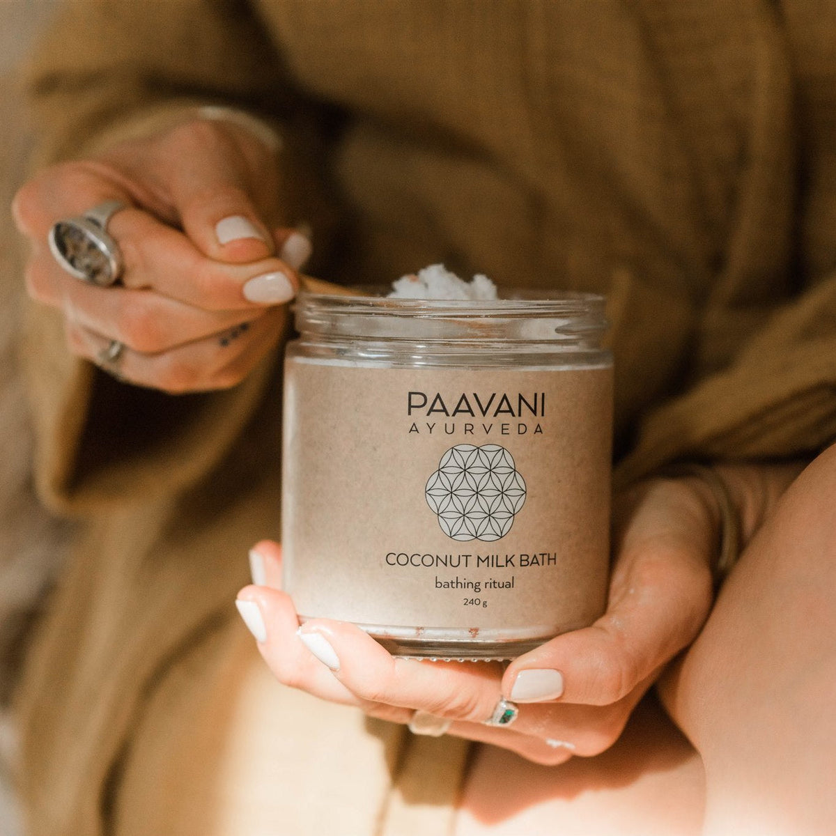 Bottle of Paavani Ayurveda Coconut Milk Bath with herbal ingredients for skin and spiritual wellness, set in a natural spa environment.