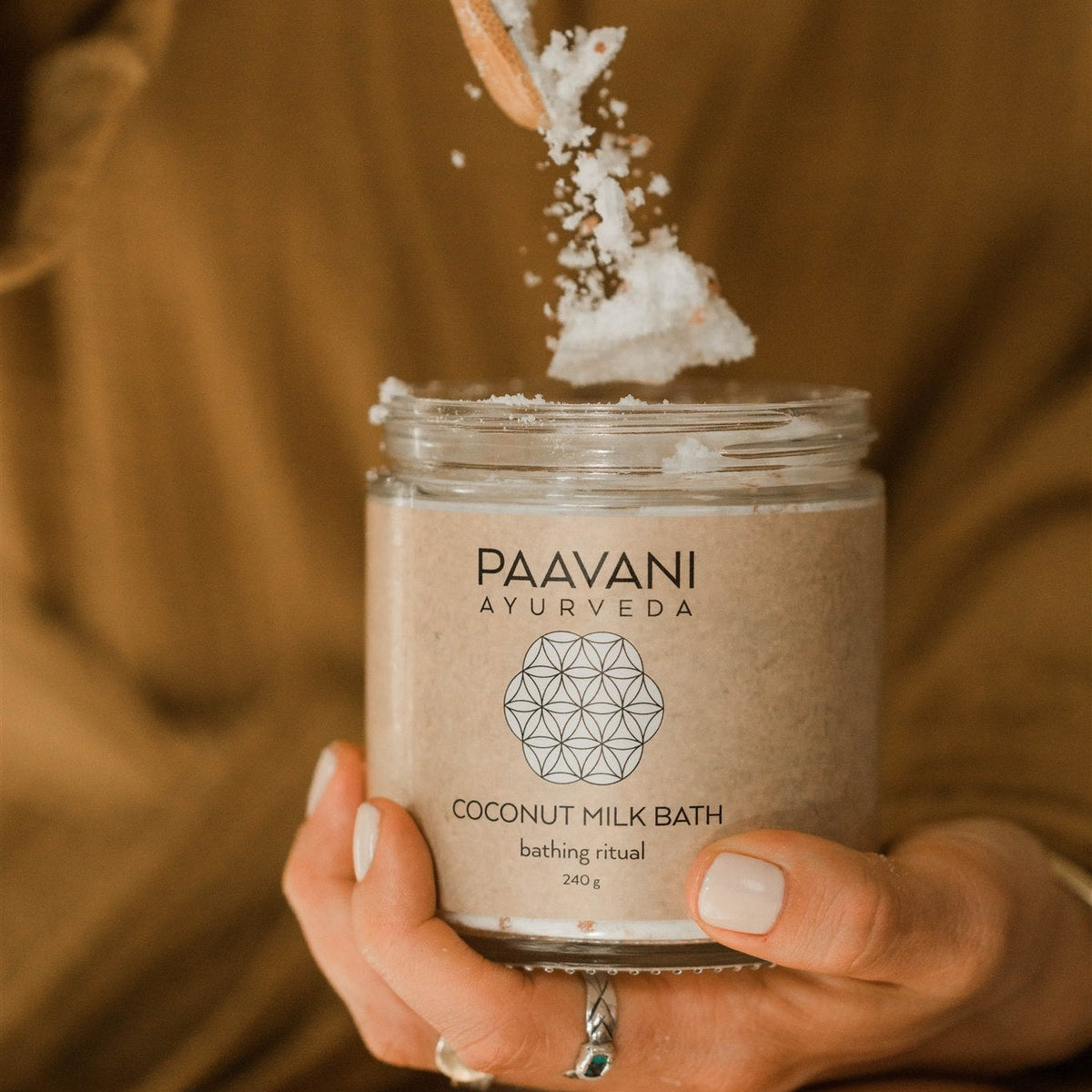 Calm scene of coconut milk bath with herbs in a wooden bowl, featuring natural skincare ingredients from Paavani Ayurveda.